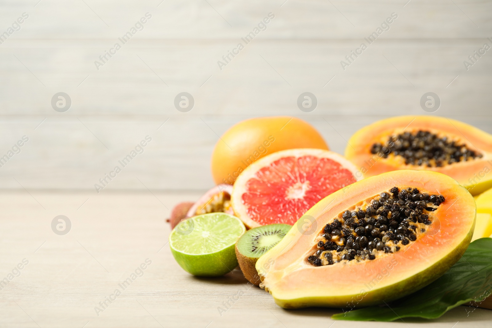 Photo of Fresh ripe papaya and other fruits on white wooden table. Space for text