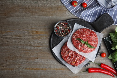 Photo of Flat lay composition with raw meat cutlets for burger on wooden table. Space for text