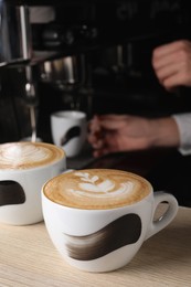Photo of Barista working in cafe, focus on counter with cups of fresh aromatic coffee