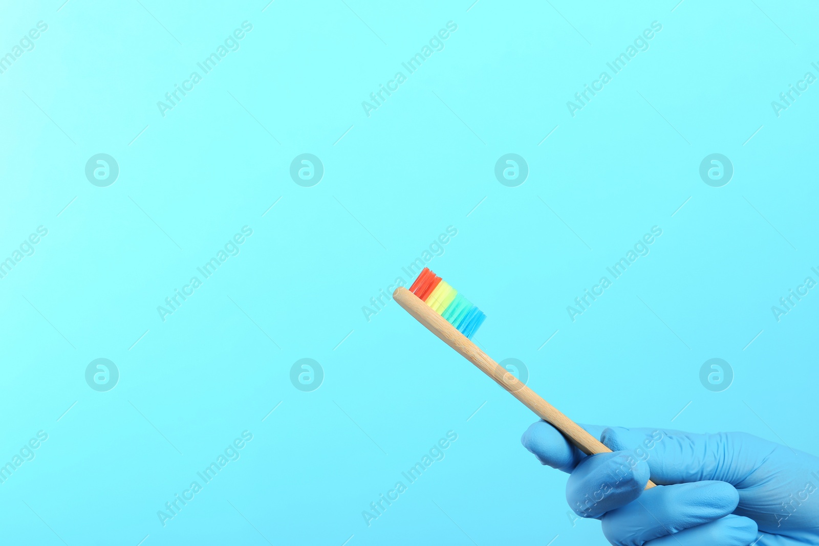 Photo of Dentist holding wooden toothbrush on color background, space for text