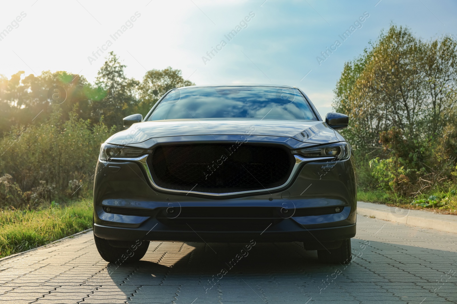 Photo of Black modern car on paved road at sunset