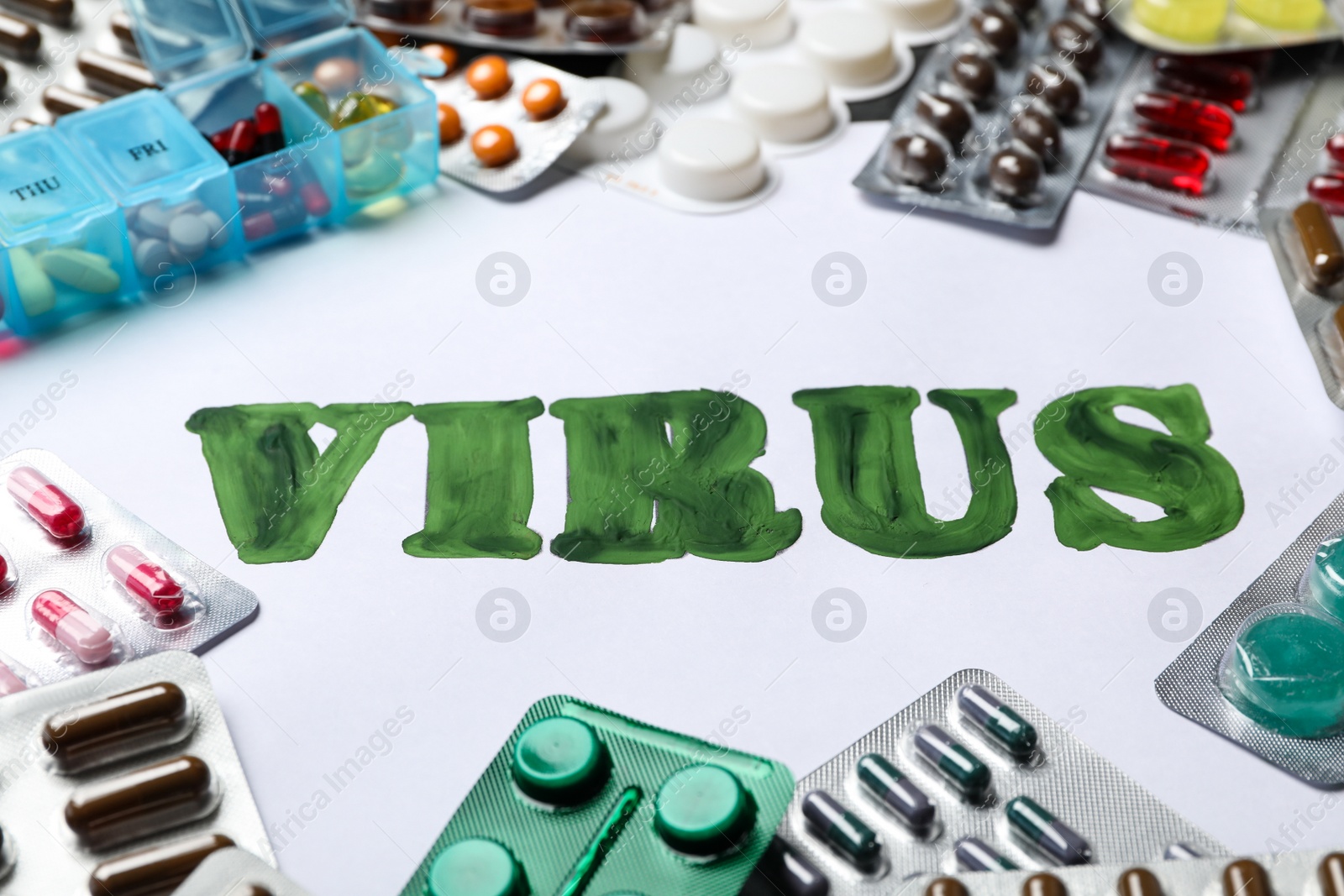 Photo of Word VIRUS and many different pills on white background, closeup