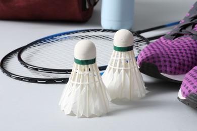 Feather badminton shuttlecocks, rackets and sneakers on gray background