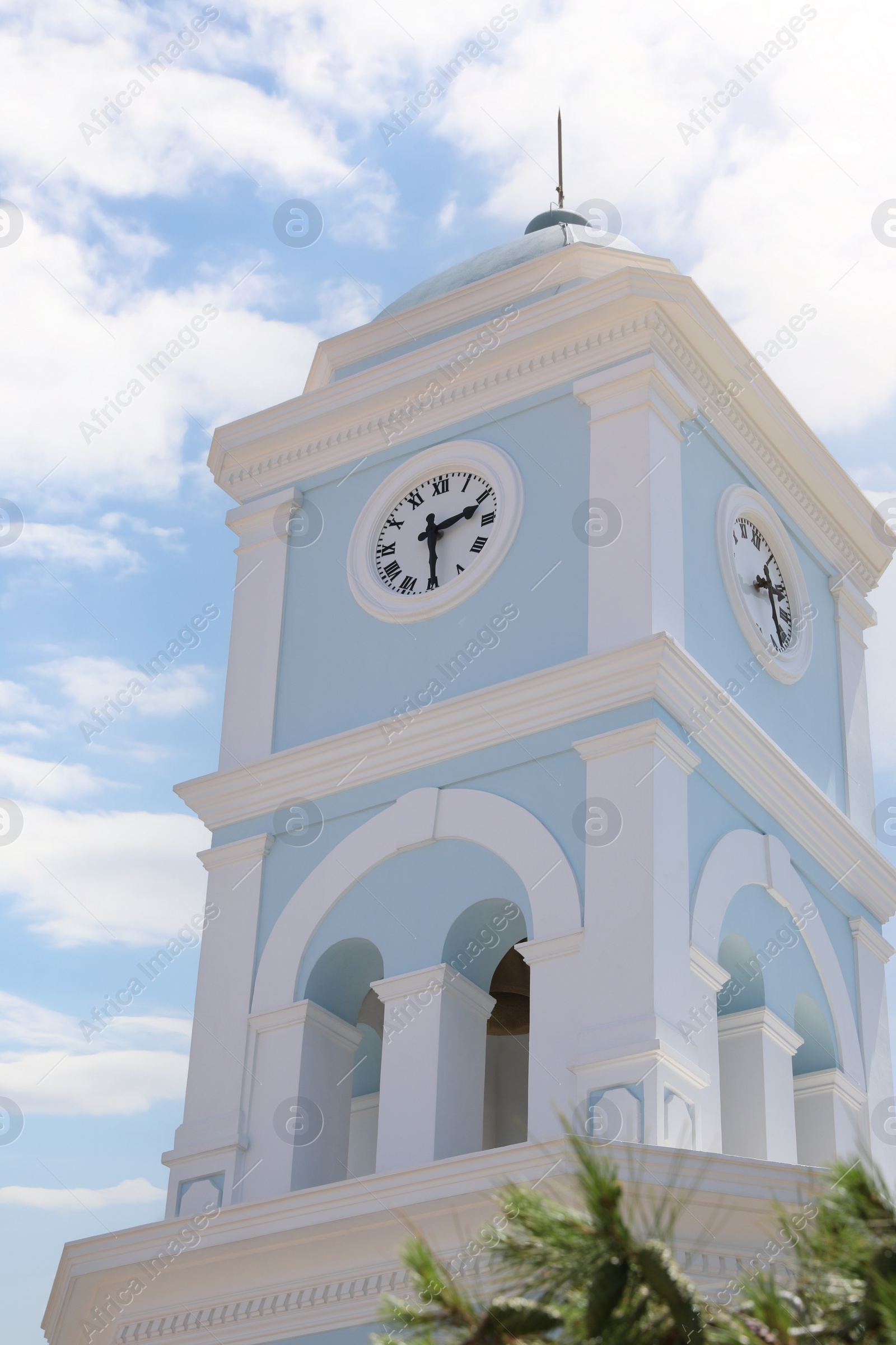 Photo of Beautiful tower with clock against blue sky, low angle view