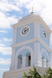 Photo of Beautiful tower with clock against blue sky, low angle view