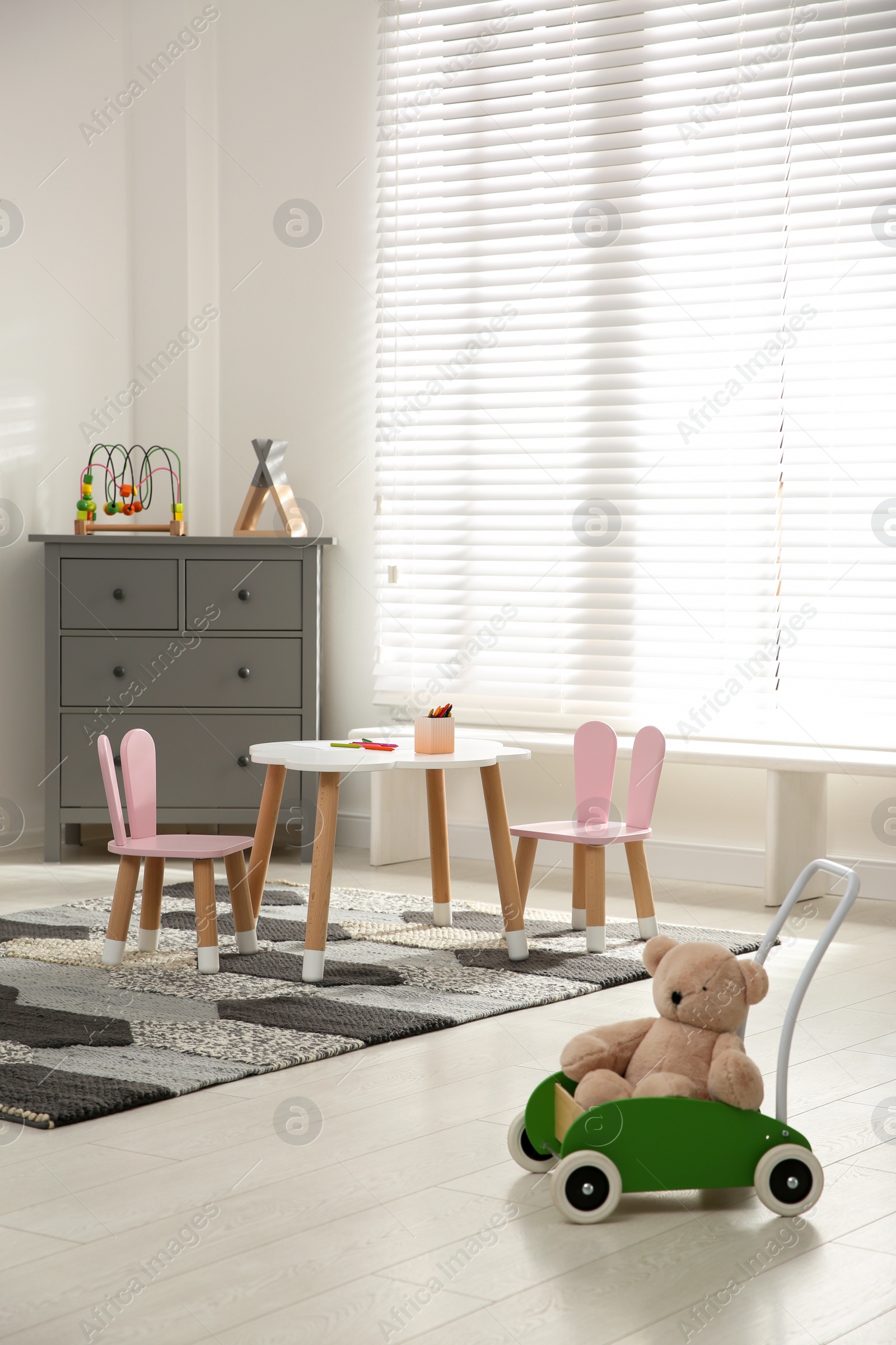 Photo of Little table and chairs with bunny ears in children's room. Interior design