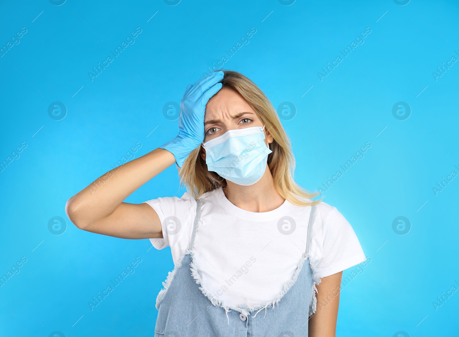 Photo of Stressed woman in protective mask on light blue background. Mental health problems during COVID-19 pandemic