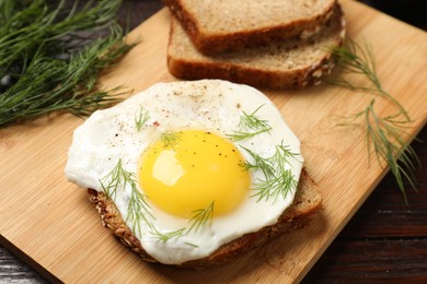 Photo of Tasty sandwich with fried egg on wooden table, closeup