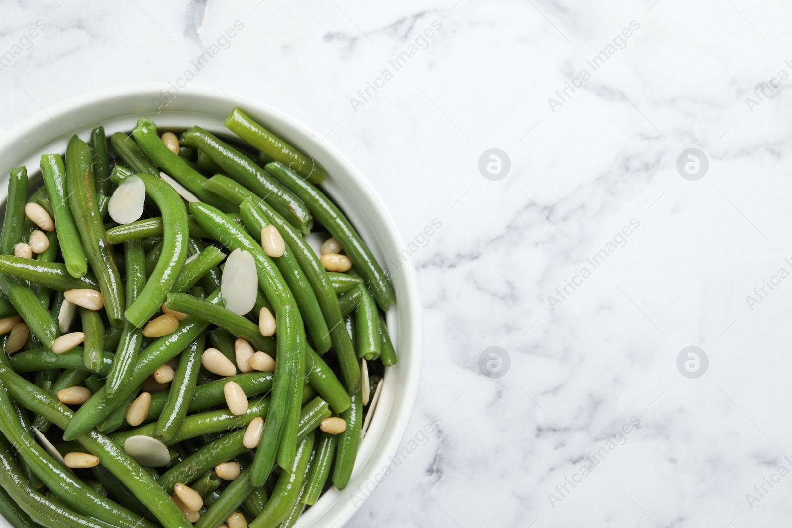 Photo of Bowl of tasty salad with green beans on white marble table, top view. Space for text