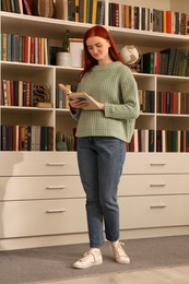 Photo of Beautiful young woman reading book in room. Home library