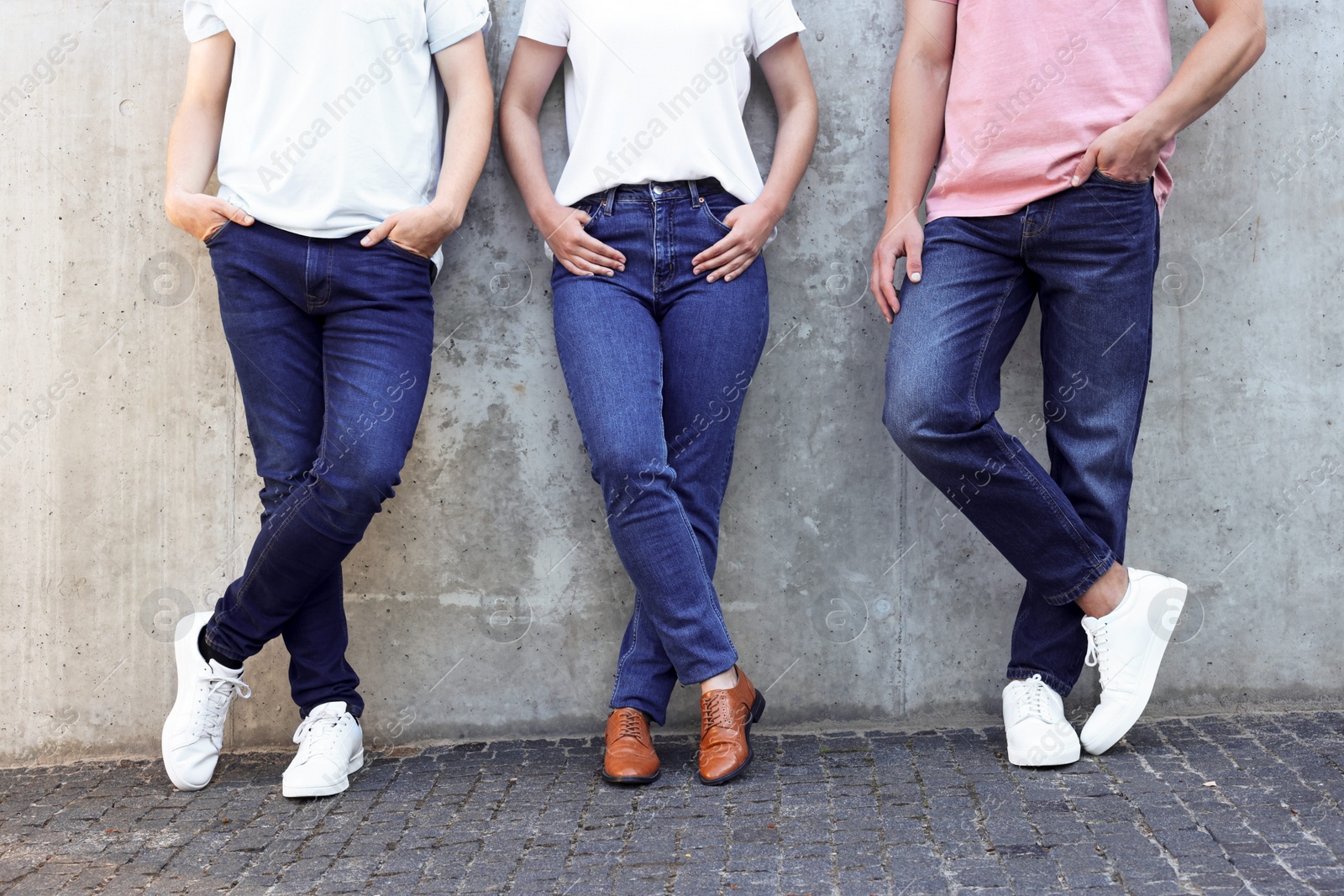 Photo of Group of people in stylish jeans near grey wall outdoors, closeup