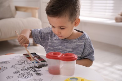 Cute child coloring drawing at table in room