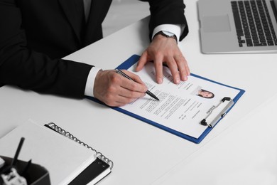 Photo of Human resources manager reading applicant's resume at table, closeup