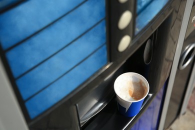 Coffee vending machine with paper cup on drip tray, above view