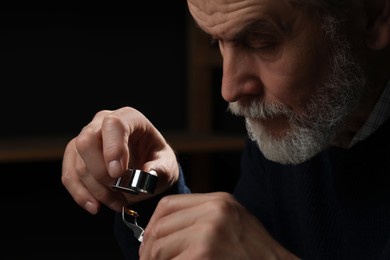 Professional jeweler working with gemstone on dark background, closeup