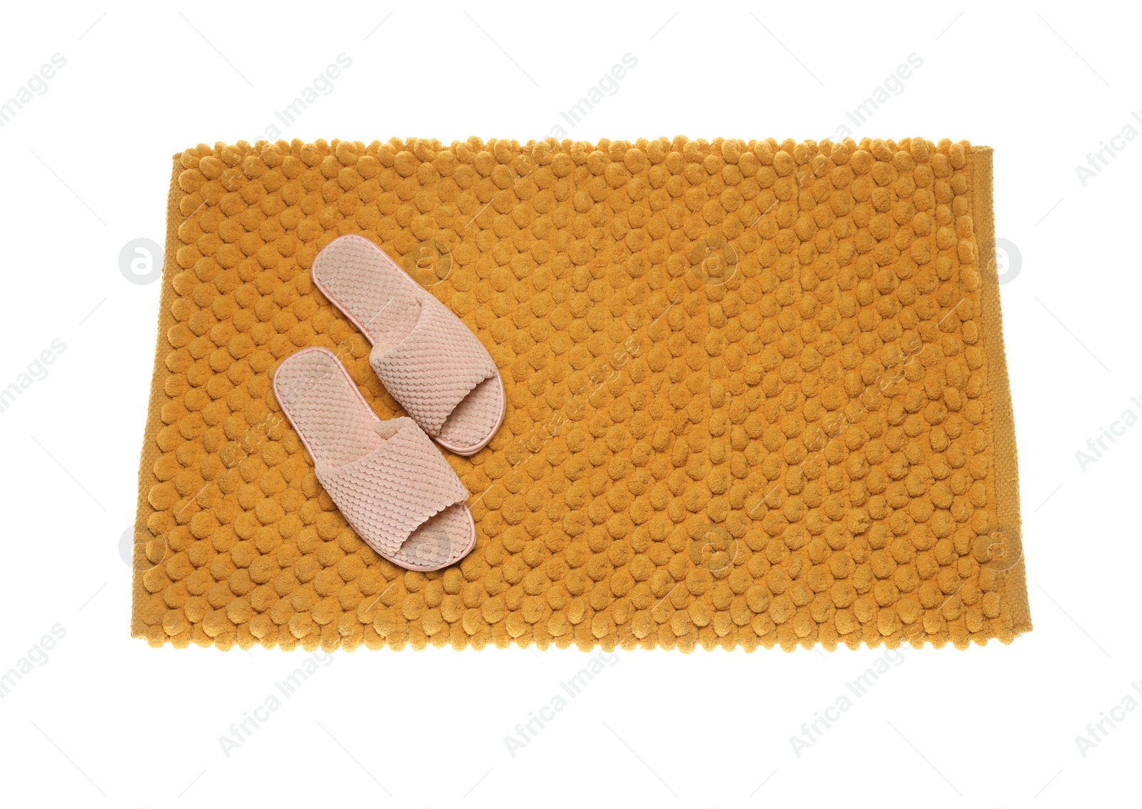 Photo of Soft orange bath mat and slippers isolated on white, top view