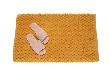 Soft orange bath mat and slippers isolated on white, top view