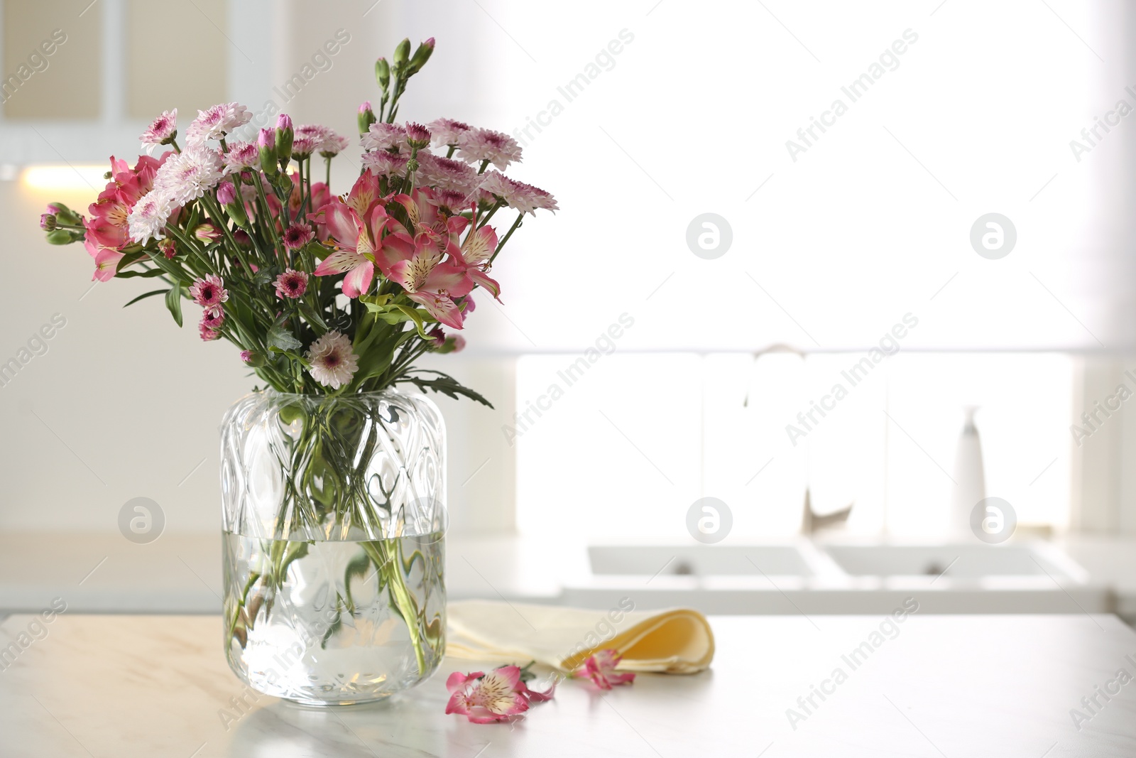 Photo of Vase with beautiful flowers on table in kitchen, space for text. Stylish element of interior design