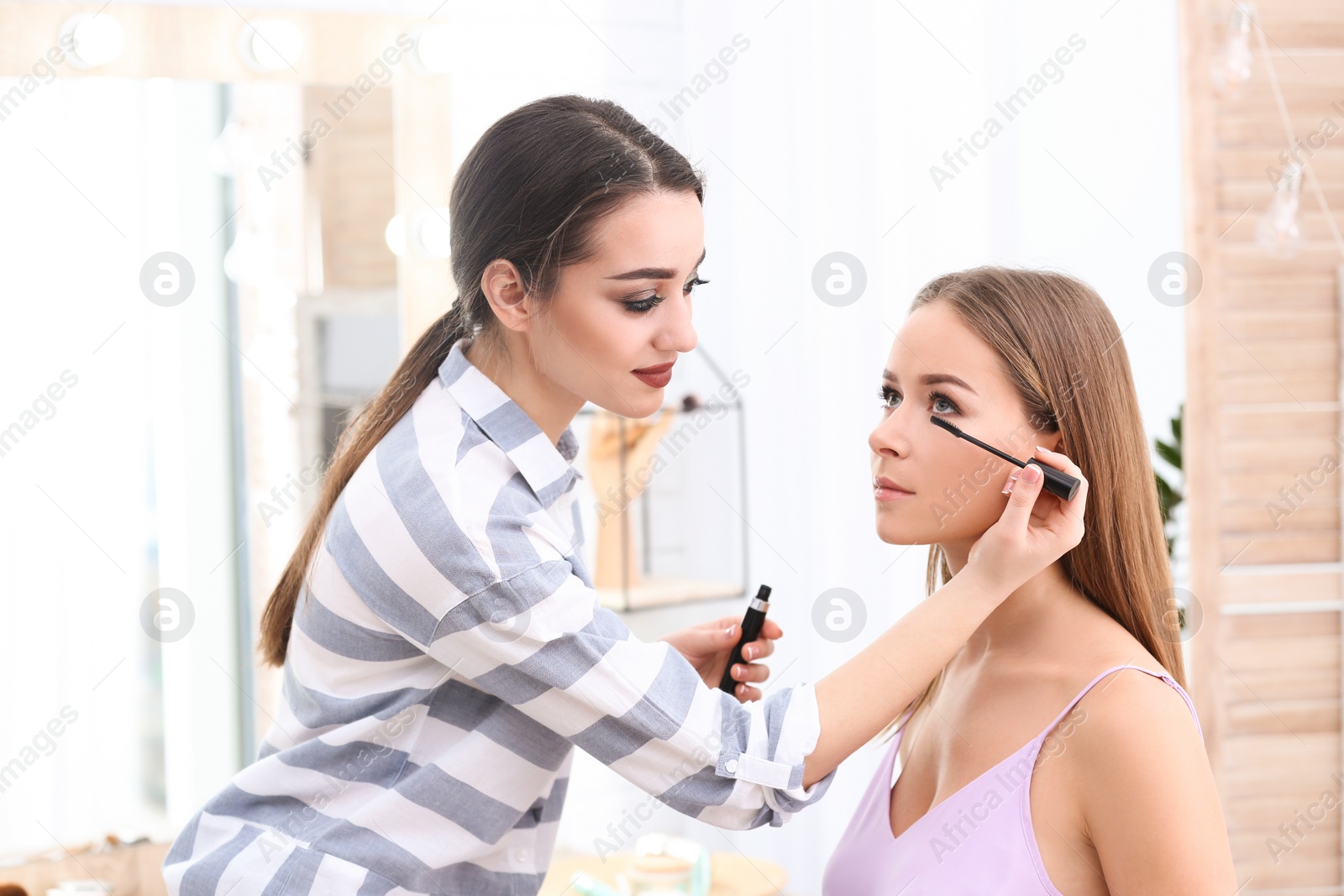 Photo of Professional visage artist applying makeup on woman's face in salon