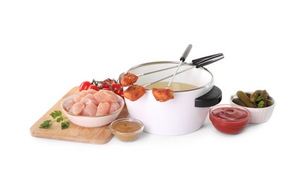 Photo of Fondue pot with oil, forks, meat pieces and other products isolated on white