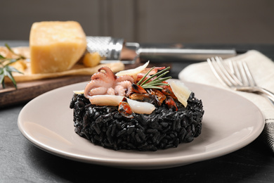 Delicious black risotto with seafood on grey table
