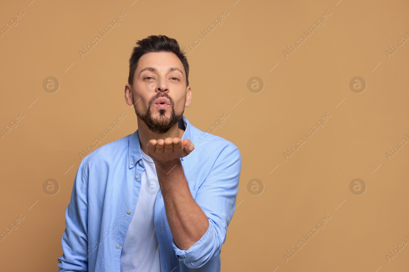 Photo of Handsome man blowing kiss on beige background. Space for text