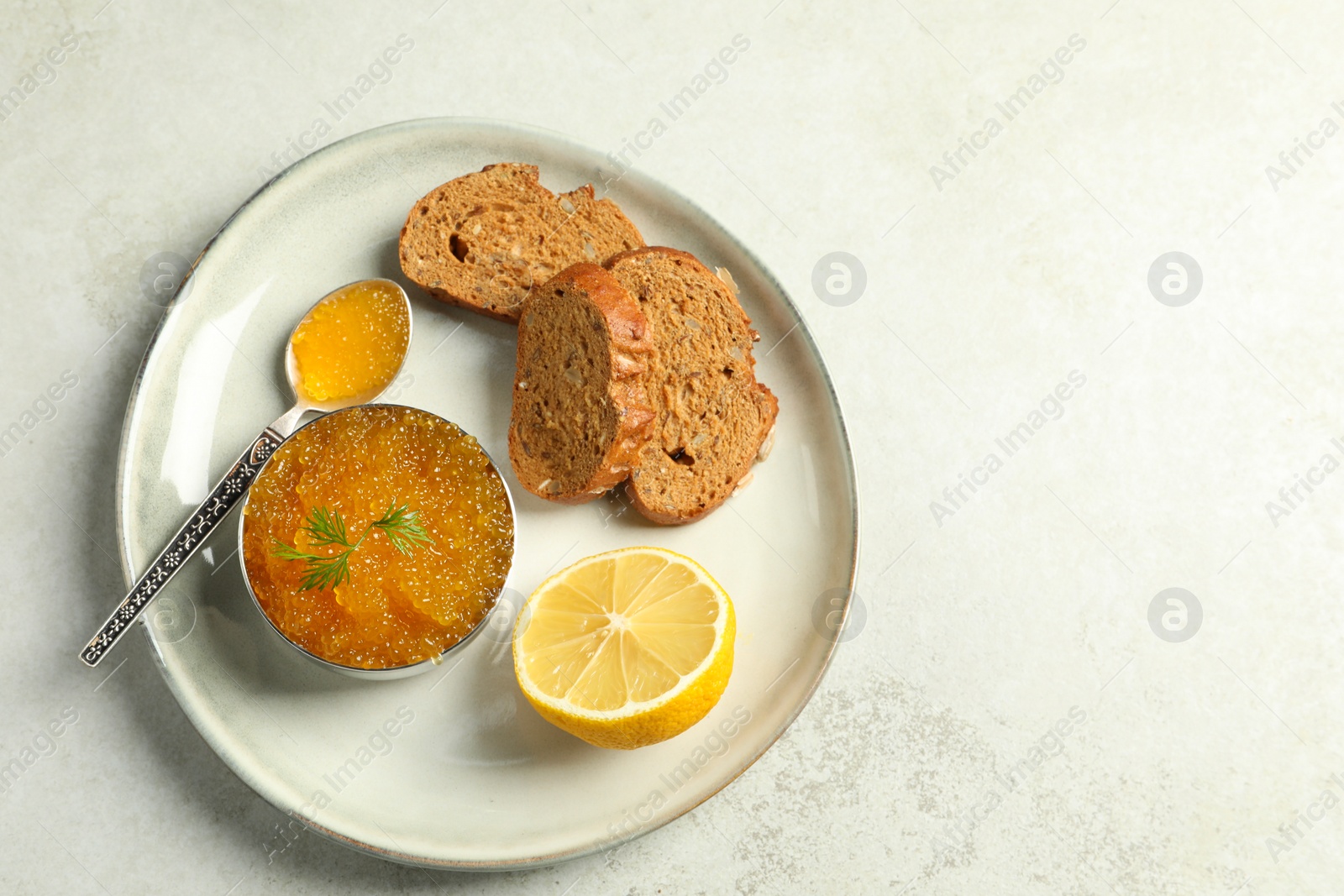 Photo of Fresh pike caviar in bowl, lemon and bread on light table, top view. Space for text