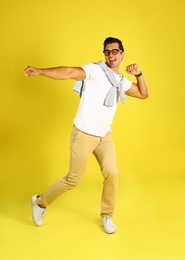 Photo of Handsome young man dancing on yellow background