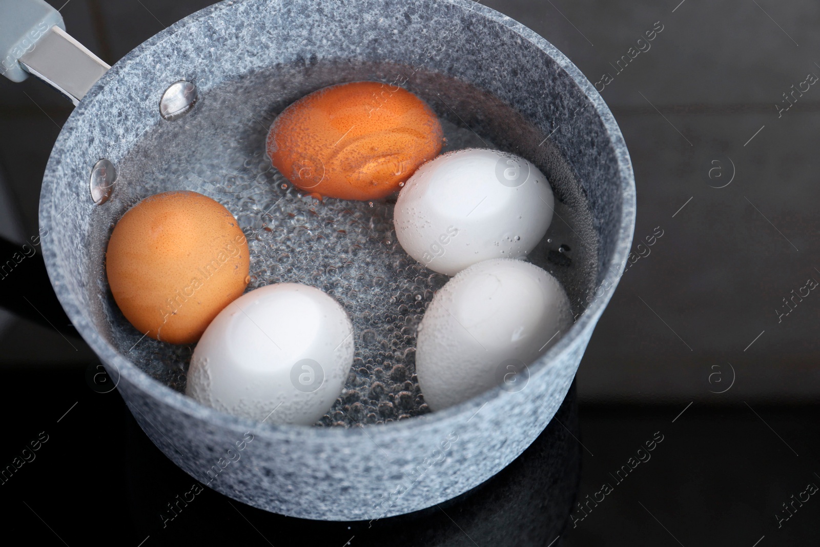 Photo of Chicken eggs boiling in saucepan on electric stove, closeup