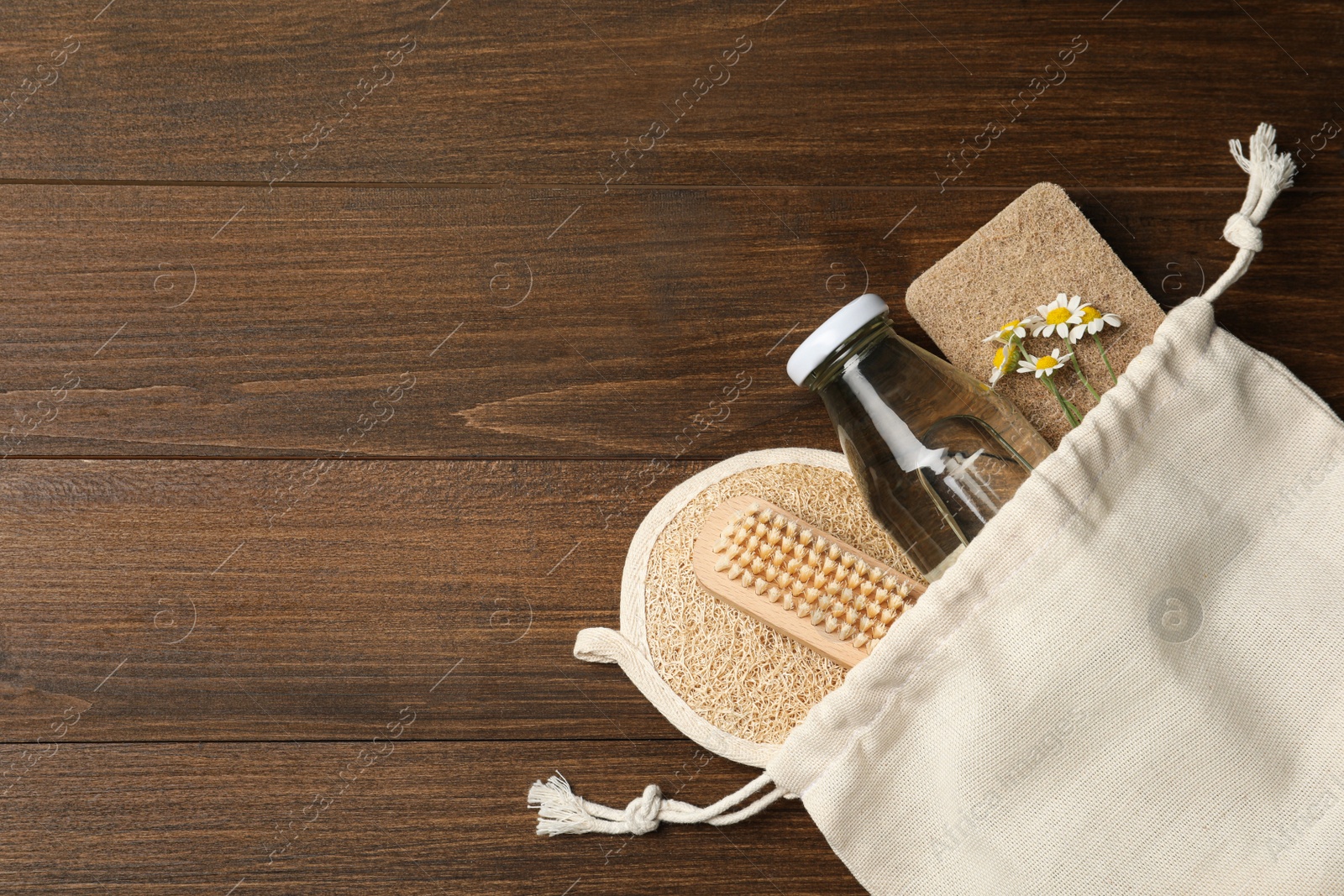 Photo of Bag with eco friendly products on wooden background, top view and space for text. Conscious consumption