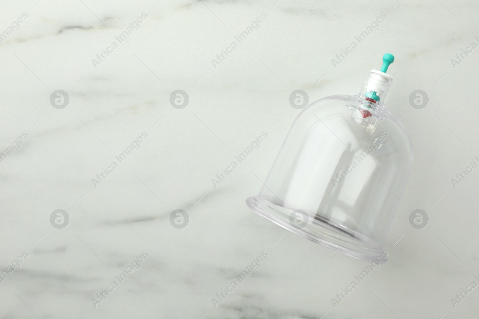 Photo of Plastic cup on white marble table, top view with space for text. Cupping therapy