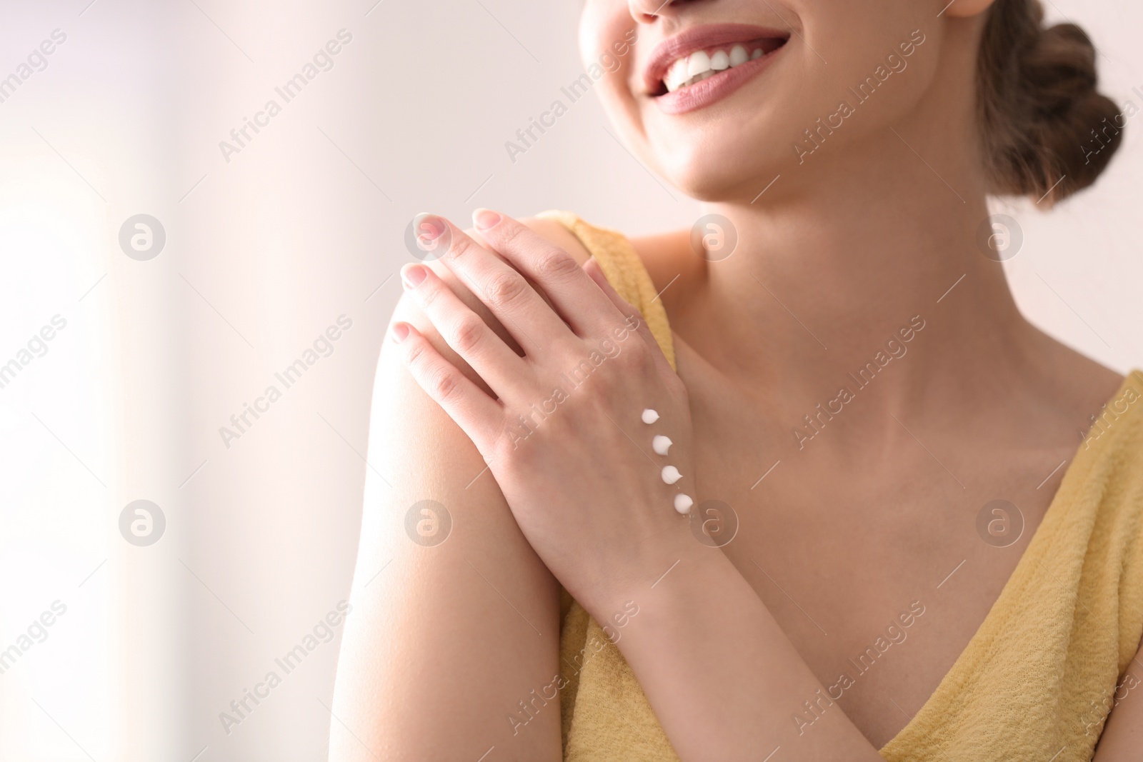 Photo of Young woman applying hand cream at home, closeup