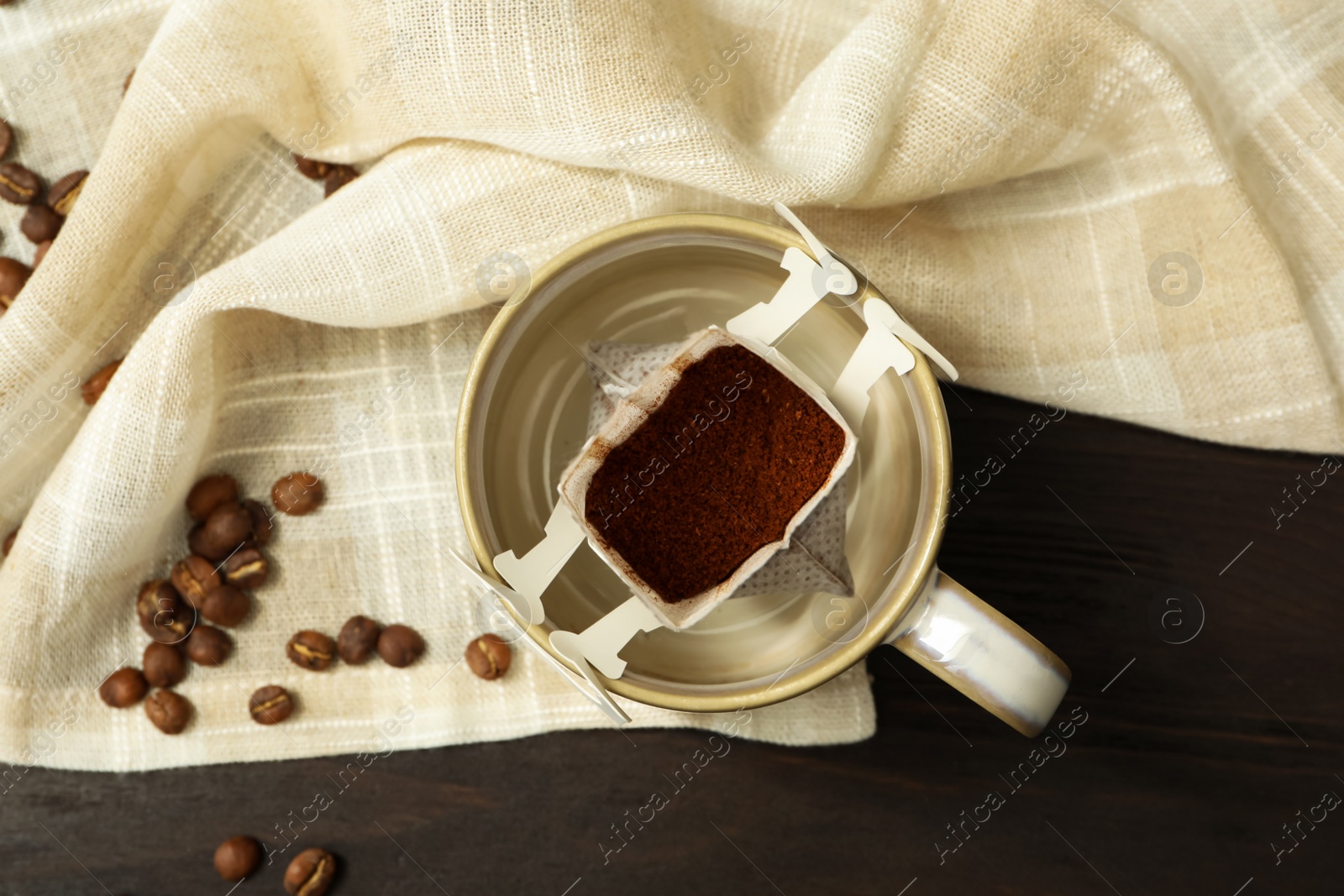 Photo of Drip coffee in cup on brown wooden table, flat lay