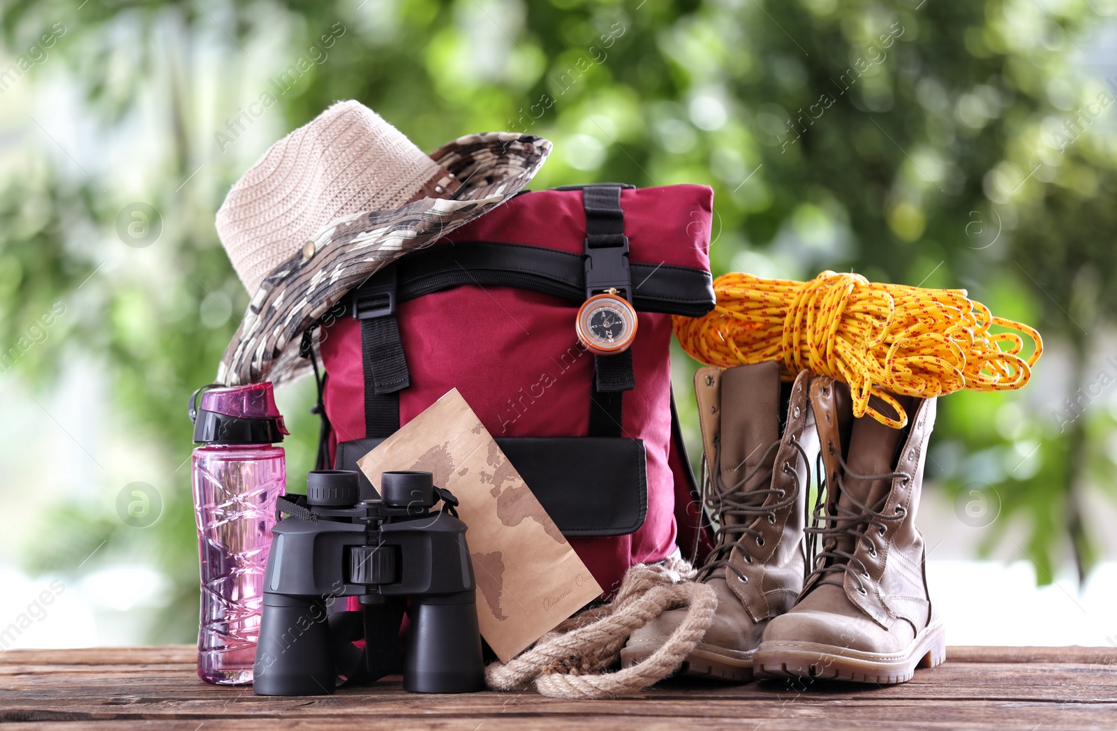Photo of Composition with backpack and camping equipment on table against blurred background