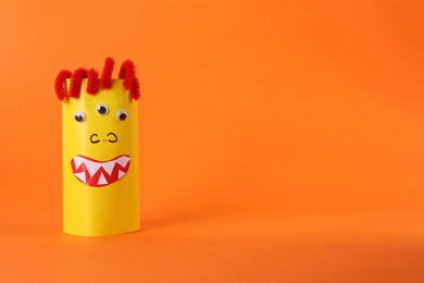 Photo of Funny yellow monster on orange background, space for text. Halloween decoration