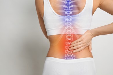 Image of Woman suffering from pain in back on light grey background, closeup. Space for text