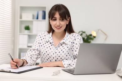 Smiling secretary working at table in office