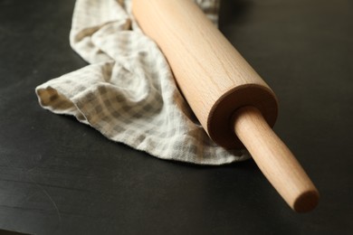 Photo of Rolling pin and kitchen towel on black table, closeup