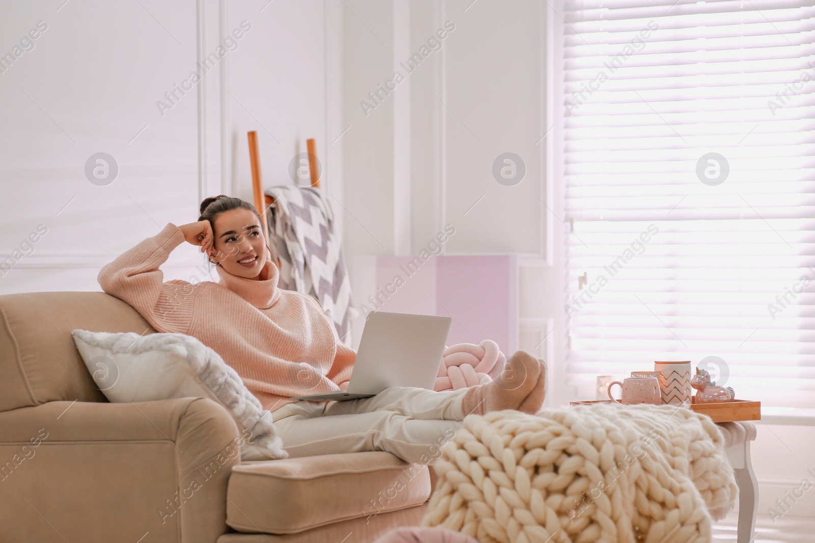 Photo of Beautiful young woman with laptop relaxing at home. Cozy atmosphere