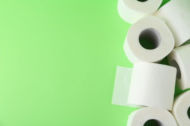 Photo of Soft toilet paper rolls on green background, flat lay. Space for text