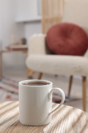 Photo of White mug of tea on wooden table indoors, space for text