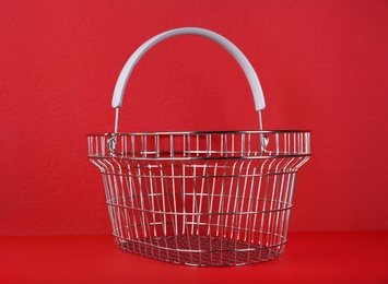 Empty metal shopping basket on red background