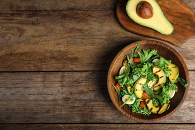 Photo of Delicious avocado salad with boiled eggs in bowl on wooden table, flat lay. Space for text