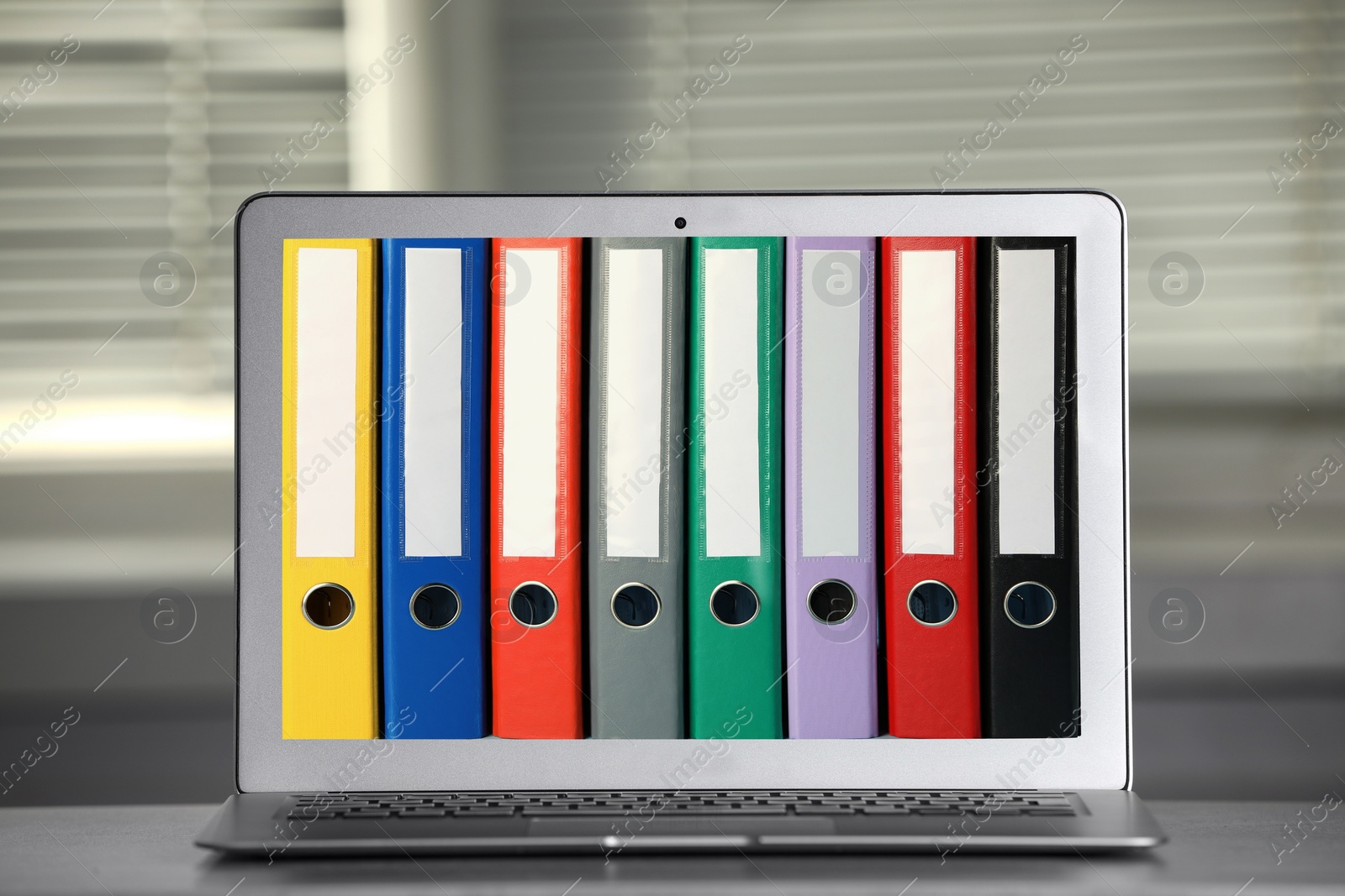 Image of Store and organize information. Modern laptop with hardcover office folders on screen