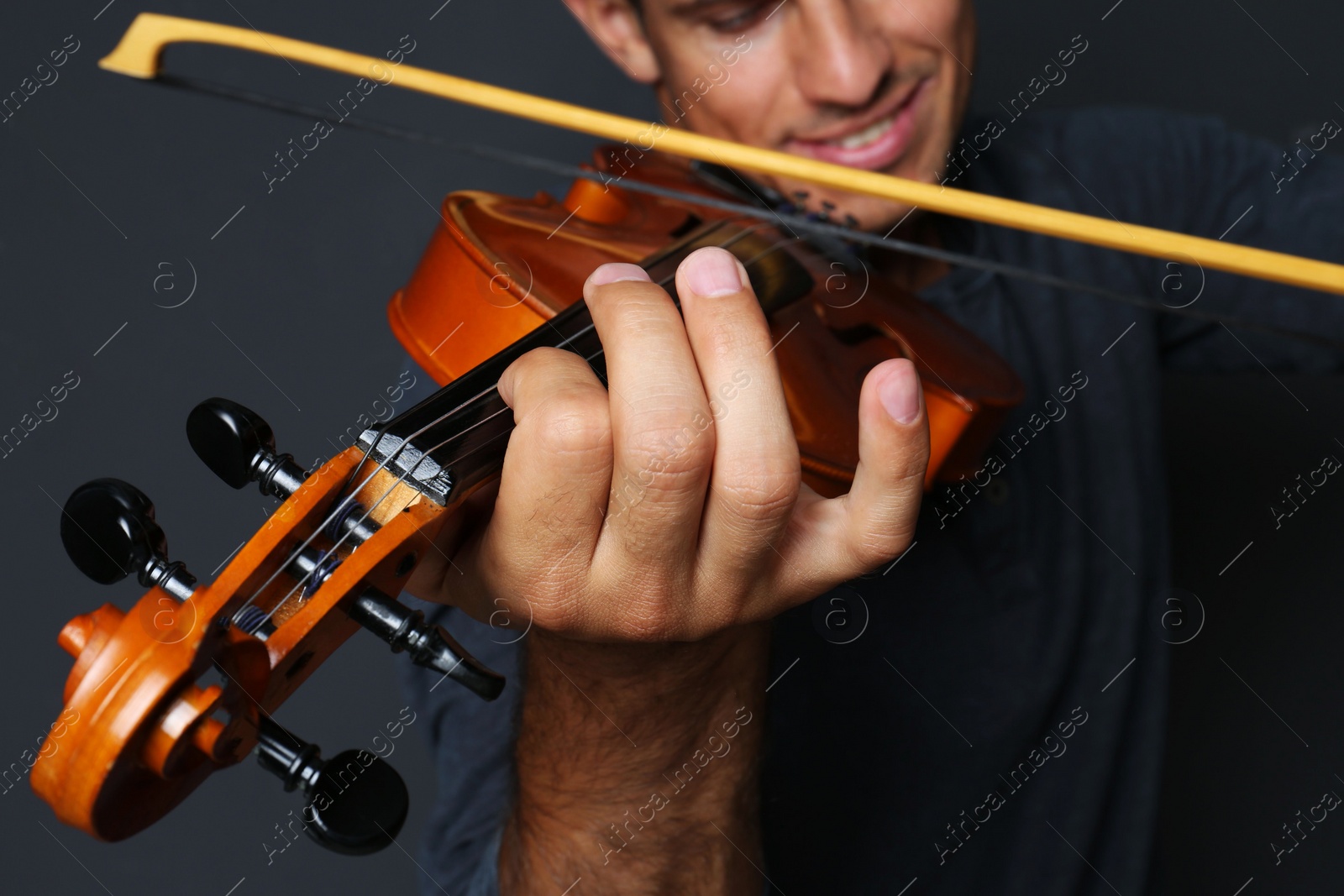 Photo of Man playing violin on black background, closeup