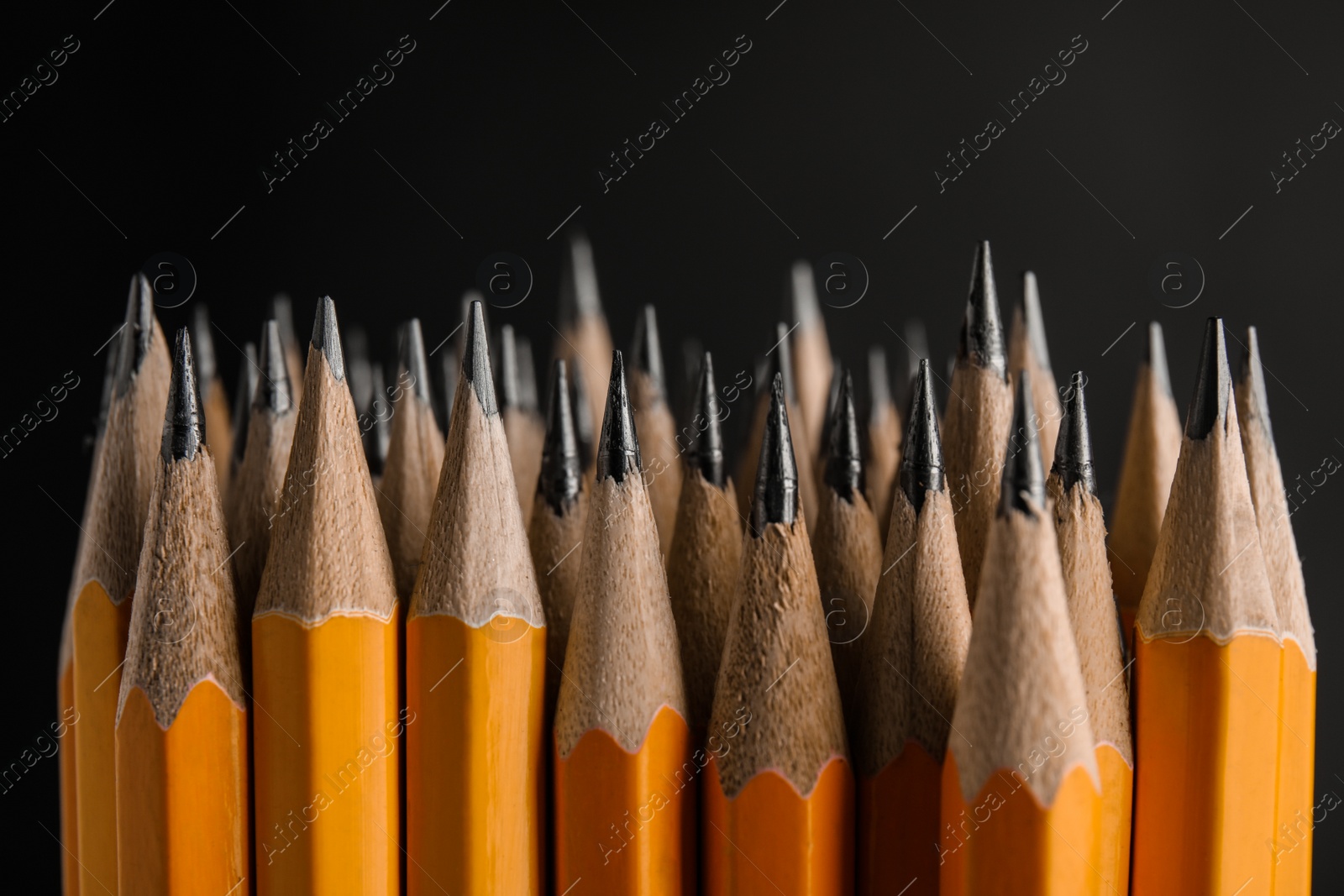 Photo of Many graphite pencils on black background, closeup