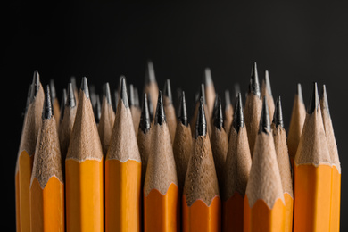 Photo of Many graphite pencils on black background, closeup