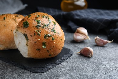 Photo of Traditional pampushka buns with garlic and herbs on grey table, closeup