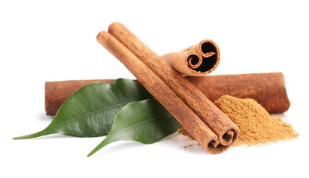 Photo of Dry aromatic cinnamon sticks, powder and green leaves isolated on white