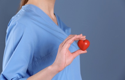 Photo of Doctor holding small heart on color background. Prevent heart attack